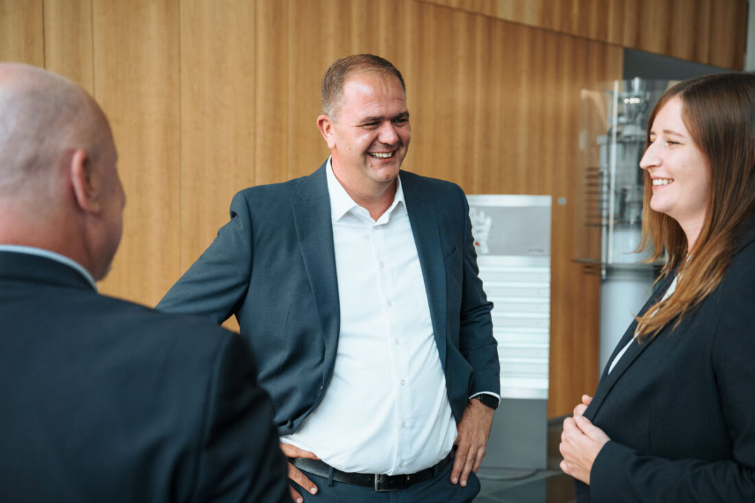Mitarbeiter lachen im Gespräch bei der Köln.Assekuranz Agentur